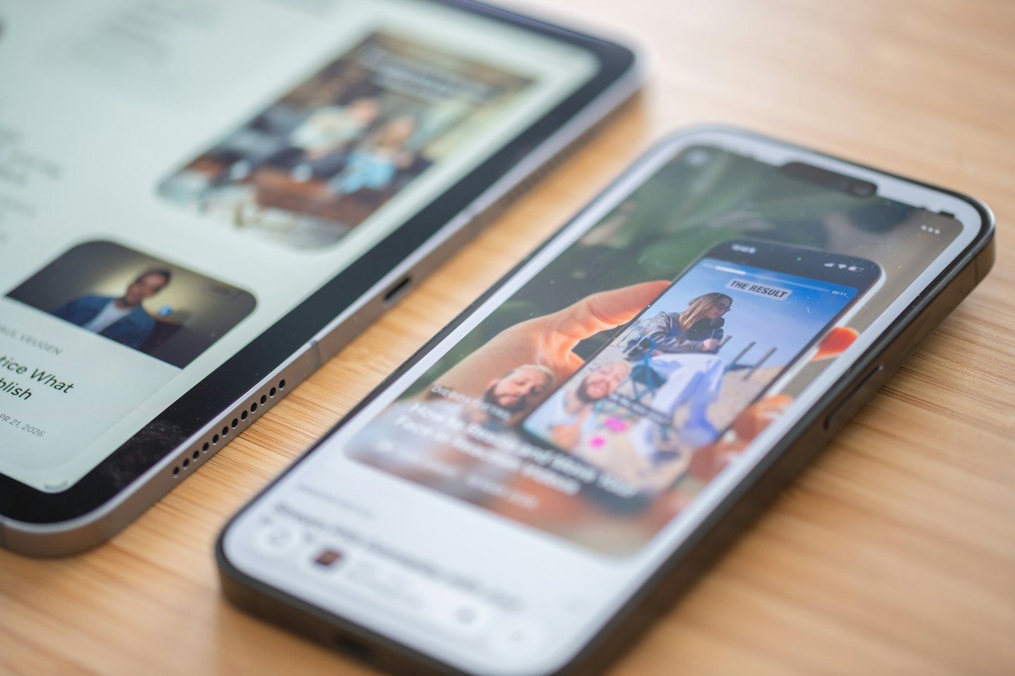 Smartphone e tablet su una scrivania di legno che mostrano contenuti digitali.